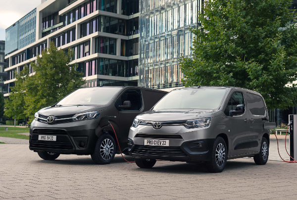 Two grey Toyota electric vans charging at a public charging station.